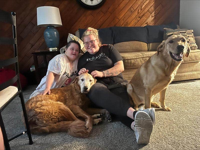 Two women sitting on the floor with their dogs.